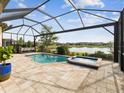 Backyard with a screened-in pool and spa overlooking a beautiful lake with a screen enclosure at 11248 Juglans Dr, Odessa, FL 33556