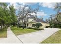 Exterior view of a yellow two-story home with a spacious driveway and lush green lawn at 16113 Ternglade Dr, Lithia, FL 33547