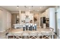 Open-concept kitchen and dining area featuring pendant lighting, island seating, and stainless-steel appliances at 1797 Trailhead Ln, Zephyrhills, FL 33541