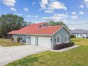Exterior view showcasing a three car garage, red tile roof and well-kept lawn at 18502 Keystone Manor Rd, Odessa, FL 33556