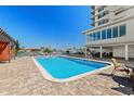 Community pool featuring lounge chairs, covered seating, and well-maintained brick patio at 223 Island Way # 2C, Clearwater Beach, FL 33767
