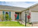 Close-up of the home's entrance, showcasing the turquoise front door, vibrant landscaping, and walkway lighting at 3410 5Th W Dr, Palmetto, FL 34221