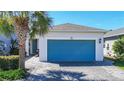 Charming single-story home featuring a blue garage door, paver driveway, and attractive landscaping with a palm tree at 5415 Los Robles Ct, Palmetto, FL 34221
