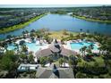 Aerial shot of the resort-style community pool, clubhouse, and surrounding lake at 9736 Sage Creek Dr, Ruskin, FL 33573