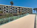 Condominium exterior showing the facade, balconies, mature landscaping and bridge for access from the beach at 1 Key Capri # 301E, Treasure Island, FL 33706