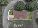 Aerial view of the home showing the roof, brick driveway, landscaping, and surrounding land at 14198 Thoroughbred Dr, Dade City, FL 33525