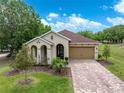 Charming single-story home with a brick driveway, a two-car garage and manicured lawn at 14198 Thoroughbred Dr, Dade City, FL 33525
