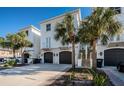 Exterior of two-story townhouses with dark gray garage doors, stone stairs, and lush landscaping at 161 Brightwater Dr # 8, Clearwater Beach, FL 33767