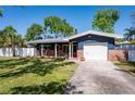 Inviting home exterior showcasing a well-maintained lawn, shade trees, and a cozy front porch with brick accents at 2019 Inner S Cir, St Petersburg, FL 33712