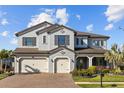 Beautiful two-story home featuring a three-car garage, manicured lawn, and a paver driveway at 28355 Picana, Wesley Chapel, FL 33543