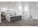 Modern, open kitchen featuring stainless steel appliances, large island with unique design, and wood-look flooring at 3422 E Powhatan Ave, Tampa, FL 33610