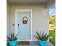 Close-up of a charming light blue front door adorned with a wreath and flanked by matching potted plants at 35168 Arya Way, Zephyrhills, FL 33541