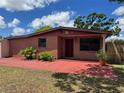 Charming brick home with red accents, featuring manicured landscaping and a cozy front porch at 6420 N Thatcher Ave, Tampa, FL 33614