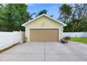 View of the detached garage with a concrete driveway and a white fence enclosing the backyard at 7701 N Dartmouth Ave, Tampa, FL 33604