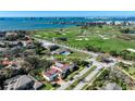Stunning aerial view of a home with a red tile roof near a golf course and waterfront at 1102 Palm View Ave, Belleair, FL 33756