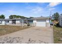Single-story home featuring an attached garage, solar panels, and well-maintained driveway at 11422 Yellowwood Ln, Port Richey, FL 34668