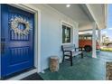 Inviting front porch with a blue door, decorative wreath, and comfortable bench seating at 2808 W Lake Ave, Tampa, FL 33607