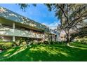 A two-story condominium with multiple balconies surrounded by lush green lawn and mature trees creating a park-like setting at 36750 Us 19 N Hwy # 18-210, Palm Harbor, FL 34684