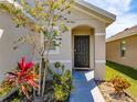 Inviting front entrance featuring a dark door, tasteful landscaping, and an arched entryway at 659 Sunlit Coral St, Ruskin, FL 33570