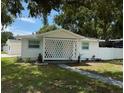 Cozy single-story home with a white lattice porch and a well-maintained lawn, surrounded by mature trees at 7202 8Th N Ave, St Petersburg, FL 33710