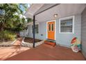 Charming front entrance featuring a covered porch, orange door, and tastefully landscaped flowerbeds at 157 7Th Sw Ave, Largo, FL 33770