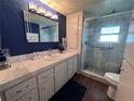 Well-lit bathroom featuring a glass-enclosed shower, modern vanity, and blue textured accent wall at 2331 Belleair Rd # 904, Clearwater, FL 33764