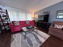 Inviting living room featuring a comfortable red couch, modern rug, and large windows, perfect for relaxation at 2331 Belleair Rd # 904, Clearwater, FL 33764
