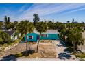 An aerial view of a light blue single story home surrounded by mature palm trees, sunny skies, and lush landscaping at 340 83Rd Ave, St Pete Beach, FL 33706