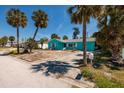 A single-story home with light blue exterior, complemented by mature palm trees and a lush yard at 340 83Rd Ave, St Pete Beach, FL 33706