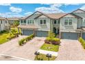 Two-story townhome showing garages, landscaping and brick paver driveway at 4663 Almada Ln, Wesley Chapel, FL 33543