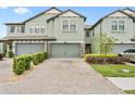 Two-story townhome with a brick paver driveway and manicured landscaping at 4663 Almada Ln, Wesley Chapel, FL 33543