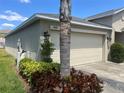 Beige colored garage door with decorative landscaping and a well-manicured lawn at 4908 Babbling Brook Ln, Wimauma, FL 33598