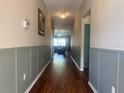Inviting hallway with wood floors and decorative wainscoting, leading to a bright living area at 4908 Babbling Brook Ln, Wimauma, FL 33598