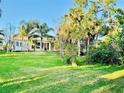 Expansive backyard featuring lush green lawn, tropical trees, and screened-in lanai at 4942 Oldham St, Sarasota, FL 34238