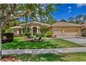 Inviting home featuring a three-car garage, lush landscaping and mature palm trees in the front yard at 5004 Waterkey Way, Tampa, FL 33647