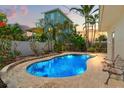 Inviting backyard pool featuring lush tropical landscaping, a surrounding brick patio, and exterior house view at 601 Boca Ciega Isle Dr, St Pete Beach, FL 33706