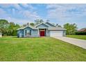 Inviting single-story home featuring a well-manicured lawn, blue siding, and a red front door at 12037 Conway St, Spring Hill, FL 34609