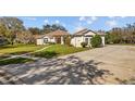 Residential house with spacious driveway, grassy lawn, and mature trees at 13750 Dowling Ln, Odessa, FL 33556