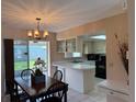 Bright kitchen featuring white cabinetry, black appliances, tile flooring, and a breakfast bar open to the dining area at 14264 Page Ave, Largo, FL 33774