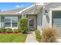 A close-up of the front entrance with a glass storm door and landscaped shrubbery at 16302 Vine Cliff Ave, Hudson, FL 34667