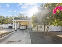 Exterior of home featuring a covered carport with a light-colored car parked under it, white picket fence and nice landscaping at 2819 N 75 St, Tampa, FL 33619