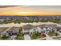 Beautiful aerial view of a neighborhood featuring lovely homes along a scenic lake at sunset at 8749 Parsons Hill Blvd, Wesley Chapel, FL 33545
