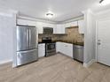 Modern kitchen features stainless steel appliances, white cabinetry, and stylish tile flooring at 9481 Highland Oak Dr # 703, Tampa, FL 33647