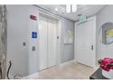 Hallway with elevator access, light walls, sconces, and tiled flooring at 130 Riviera Dunes Way # 203, Palmetto, FL 34221