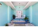 Cozy covered front porch with a white rocking chair, potted plants, and a cute 'hello' decoration at 321 Bahia Vista Dr, Indian Rocks Beach, FL 33785