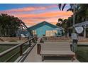 Back exterior features a wooden bench and dock overlooking the canal and patio with seating and an outdoor grill at 321 Bahia Vista Dr, Indian Rocks Beach, FL 33785