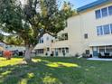 Exterior view of the condo building showcases large shade tree and lush green lawn at 5750 80Th N St # B203, St Petersburg, FL 33709