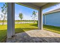 Covered patio view showcasing a serene backyard, a pond, and mature trees, perfect for outdoor relaxation at 7334 Ashcroft Dr, Wesley Chapel, FL 33545