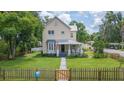Classic two-story house with a charming picket fence, featuring a well-kept lawn and mature trees at 14006 5Th St, Dade City, FL 33525