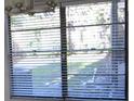 A window with white blinds overlooks a landscaped front yard, providing privacy and natural light at 4118 Dellbrook Dr, Tampa, FL 33624